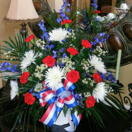 Large red, white, and blue floral standing spray with ribbon