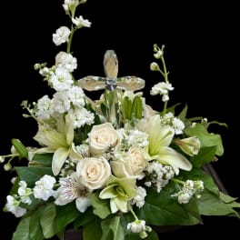 White floral arrangement with roses, lilies, and a crystal cross