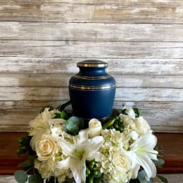 White floral urn arrangement with lilies and roses around a blue urn