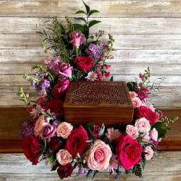 Floral arrangement around a wooden urn box with pink and red roses
