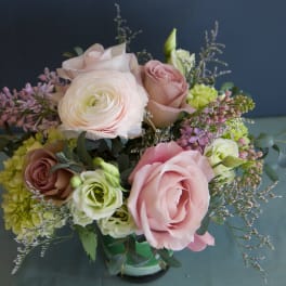 Bouquet of pink and white roses with purple filler flowers in a glass vase