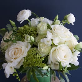 White roses and small white blooms arranged in a green vase