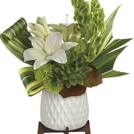 White lilies and green succulents in a white vase