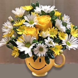 Yellow and white flower bouquet in a smiley-face mug