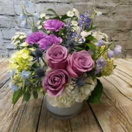 Pink roses and purple flowers arranged in a white vase
