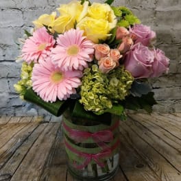 Bouquet of pink and yellow flowers in a glass vase with ribbon