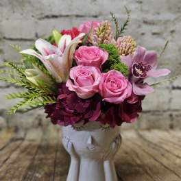 Pink roses and lilies arranged in a white ceramic vase