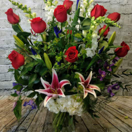 Large bouquet of red roses, white lilies, and purple flowers in a glass vase
