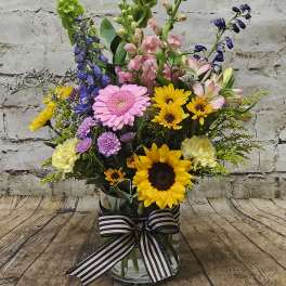 Mixed bouquet in a glass vase with sunflowers, gerberas, and snapdragons