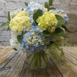Blue and pale green hydrangea bouquet in a clear glass vase