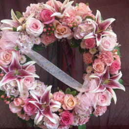 Heart-shaped floral wreath with pink roses and lilies on a stand