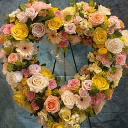 Heart-shaped floral wreath with roses, gerbera daisies, and yellow blooms