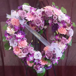 Heart-shaped floral wreath with pink and purple roses, orchids, and daisies