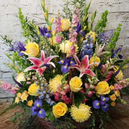 Large basket arrangement with yellow roses, pink lilies, and purple irises