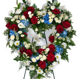 Heart-shaped standing wreath of red, white, and blue flowers on an easel