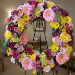 Colorful floral wreath on a black stand with pink, yellow, and purple blooms