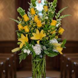 Yellow roses and lilies arranged in a clear glass vase