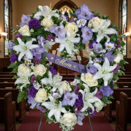 Heart-shaped floral wreath with white lilies, roses, and purple blooms