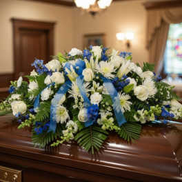 White and blue floral casket spray on a polished coffin