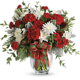 Red and white floral arrangement in a glass vase with a plaid ribbon