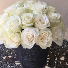 Compact arrangement of ivory roses in a black textured vase