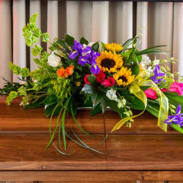 Colorful floral casket spray with sunflowers, roses, and orchids