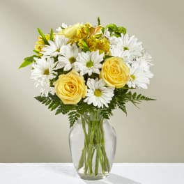 Yellow roses and white daisies in a clear glass vase