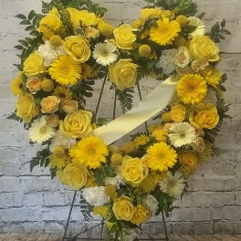 Yellow floral heart wreath on a stand with a pale ribbon