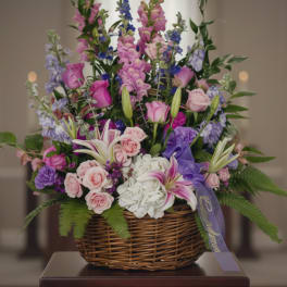Basket arrangement of pink, purple, and white flowers with a ribbon