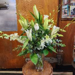 White lilies and orchids arranged in a clear glass vase