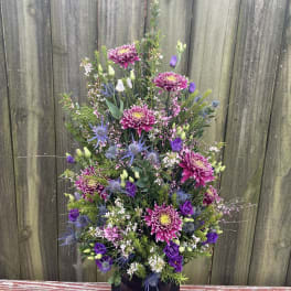 Tall bouquet of purple and pink flowers in a black vase