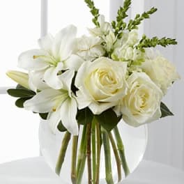 White roses and lilies arranged in a clear glass vase