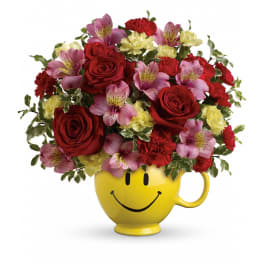 Bouquet of red roses, pink alstroemeria, and carnations in a yellow smiley-face mug