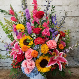 Large mixed flower arrangement in a white pedestal vase