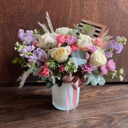 Mixed bouquet of pink, white, and lavender flowers in a white vase