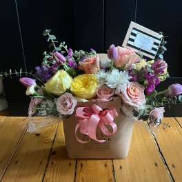 Mixed pastel flower arrangement in a square box with a pink ribbon