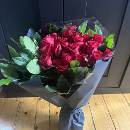 Bouquet of red roses wrapped in dark paper