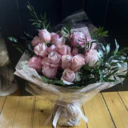 Bouquet of pale pink roses wrapped in paper with a ribbon