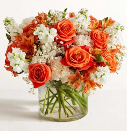 Bouquet of orange roses and white flowers in a clear glass vase