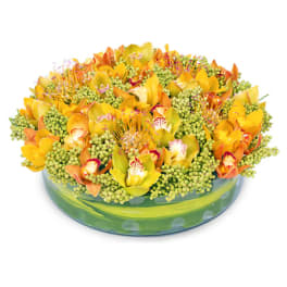 Yellow and orange orchid arrangement in a low glass bowl
