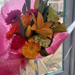 Bouquet of orange lilies, gerbera daisies, and pink chrysanthemums wrapped in pink paper