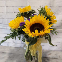 Sunflower bouquet in a glass vase with yellow ribbon