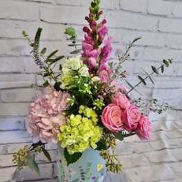 Pink and yellow mixed flower arrangement in a painted vase
