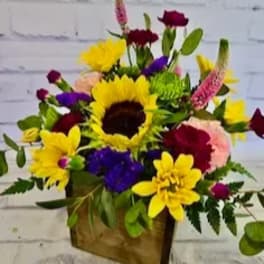 Mixed bouquet with sunflowers, carnations, and purple blooms in a wooden box