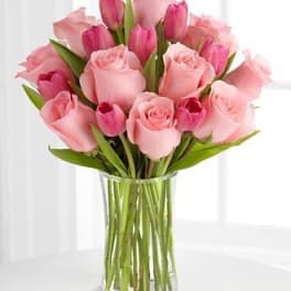Pink roses and tulips arranged in a clear glass vase