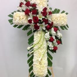 Cross-shaped floral tribute with red and white flowers on an easel