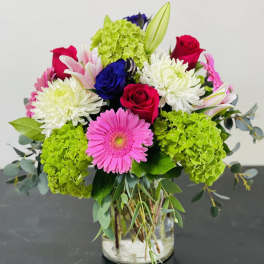 Mixed bouquet with roses, gerbera daisies, chrysanthemums, and hydrangeas in a glass vase
