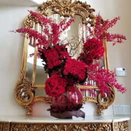 Red rose arrangement in a glass vase with pink branching accents