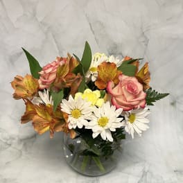 Bouquet of pink roses and white daisies in a round glass vase