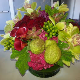 Colorful floral arrangement in a glass bowl with orchids and hydrangeas